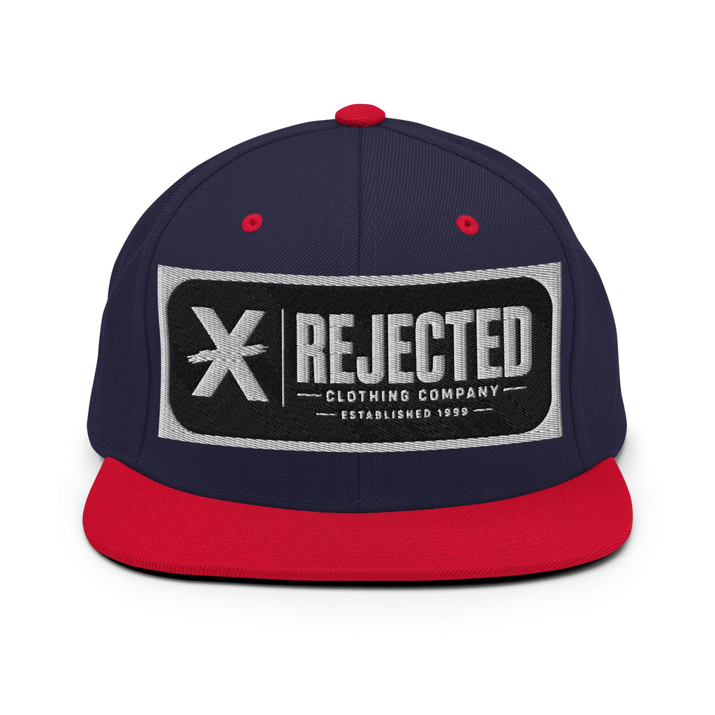 All-black snapback with an embroidered Rejected Clothing Company Established 1999 patch and a green undervisor