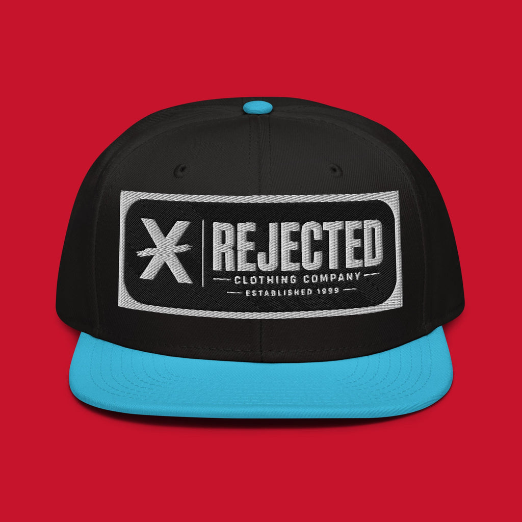 Black snapback with a teal brim and an embroidered Rejected Clothing Company Established 1999 patch
