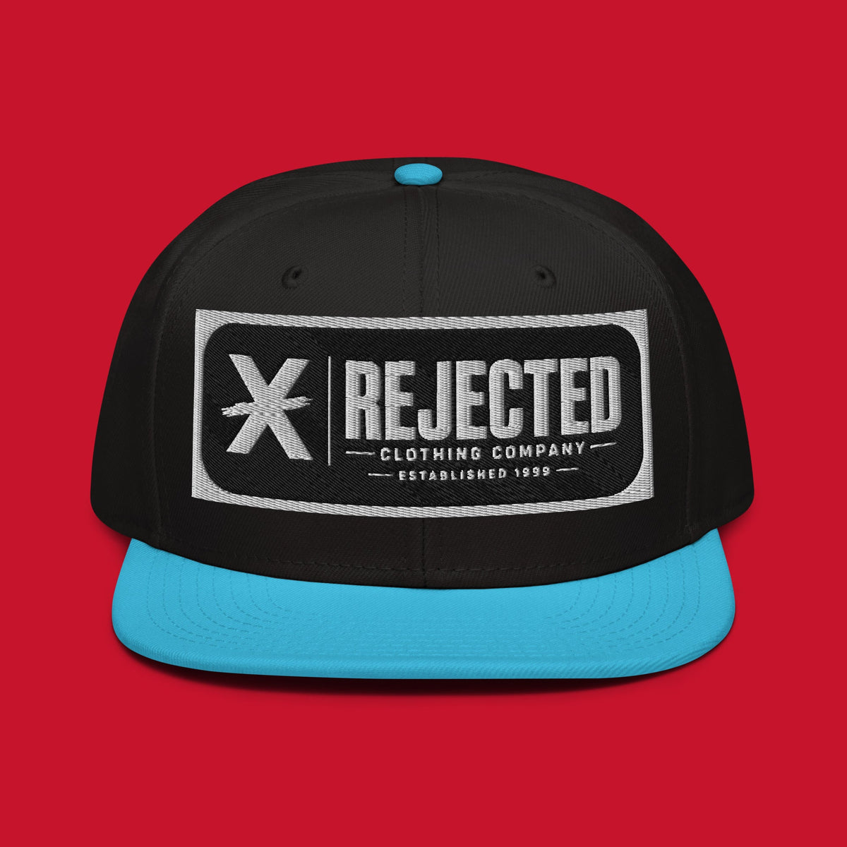 Black snapback with a teal brim and an embroidered Rejected Clothing Company Established 1999 patch