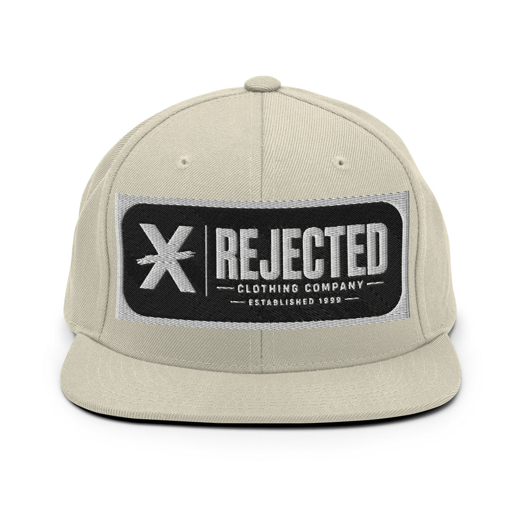 All-black snapback with an embroidered Rejected Clothing Company Established 1999 patch and a green undervisor