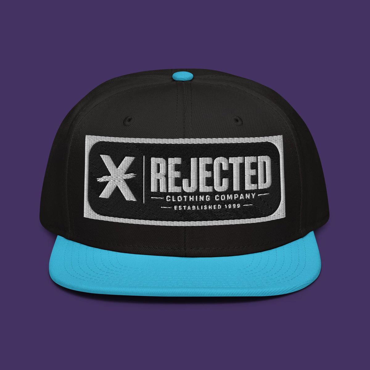 Black snapback with a teal brim and an embroidered Rejected Clothing Company Established 1999 patch