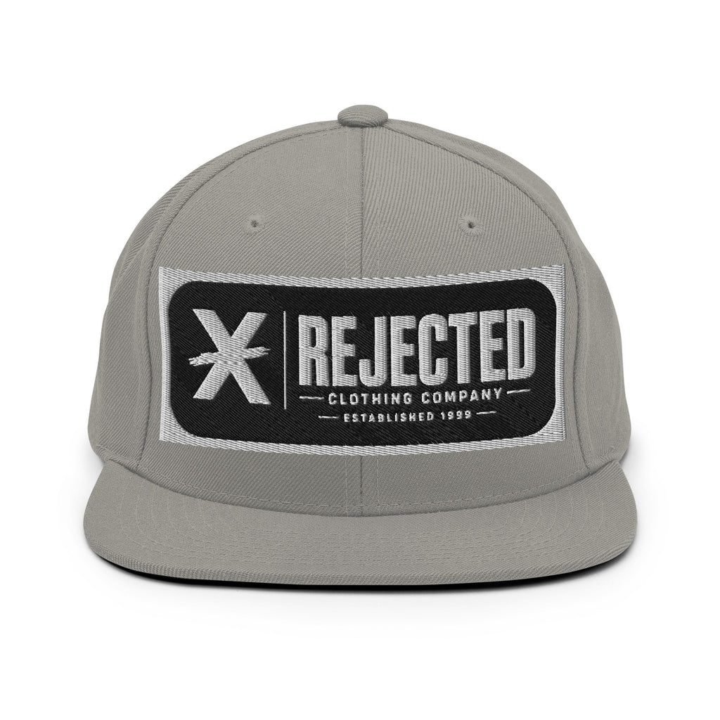 All-black snapback with an embroidered Rejected Clothing Company Established 1999 patch and a green undervisor