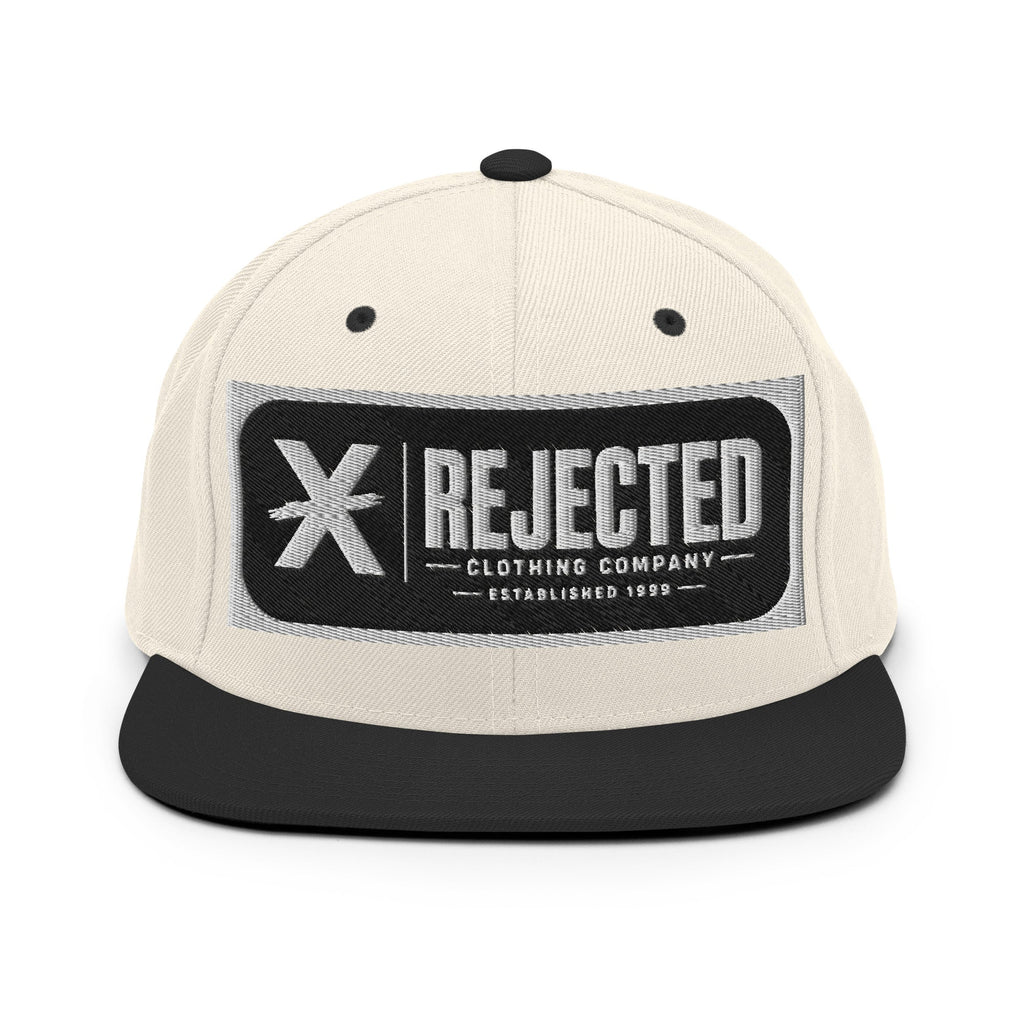 All-black snapback with an embroidered Rejected Clothing Company Established 1999 patch and a green undervisor