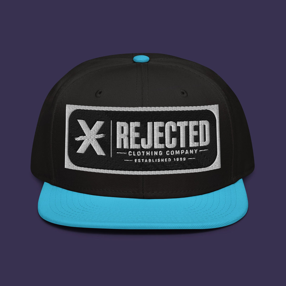 Black snapback with a teal brim and an embroidered Rejected Clothing Company Established 1999 patch