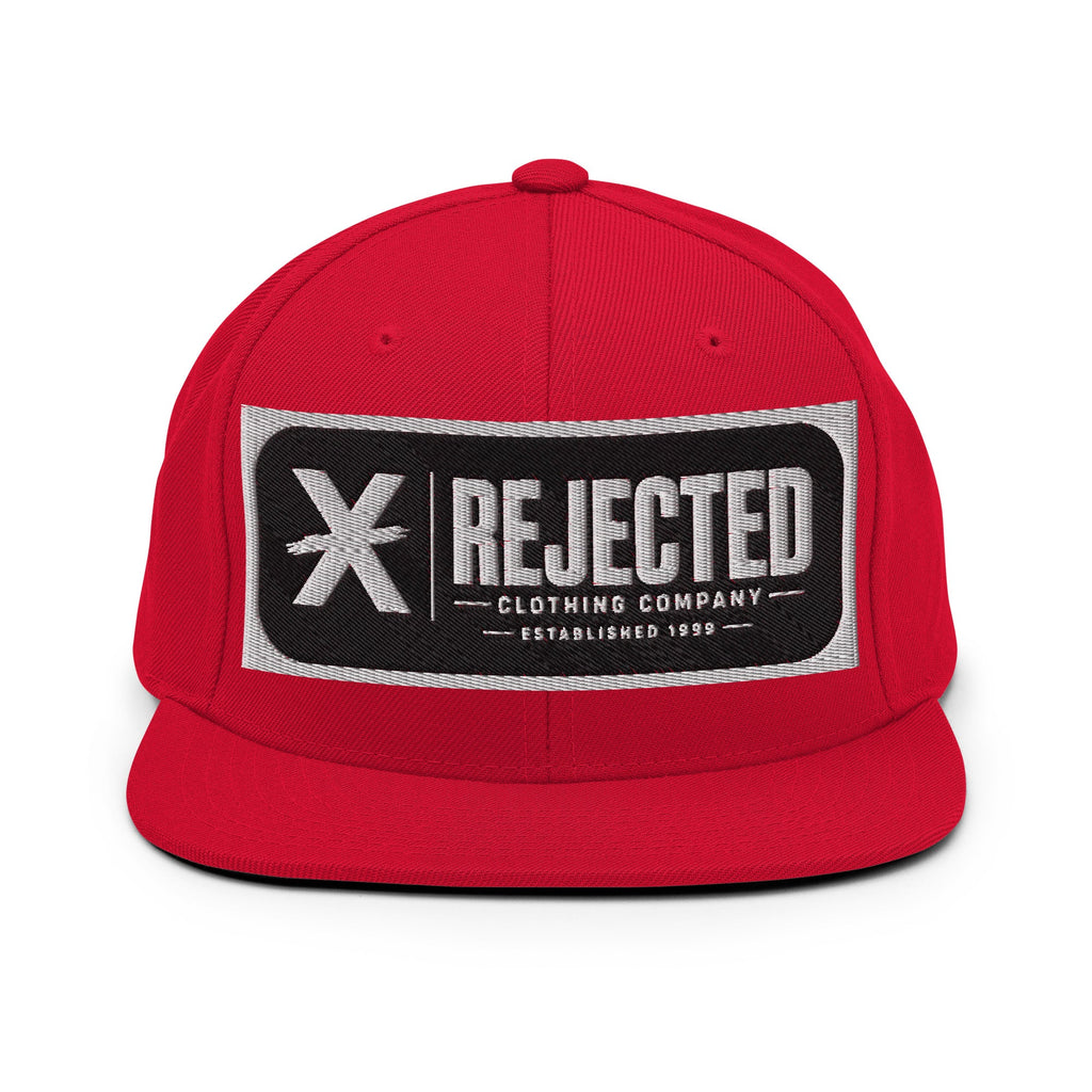 All-black snapback with an embroidered Rejected Clothing Company Established 1999 patch and a green undervisor