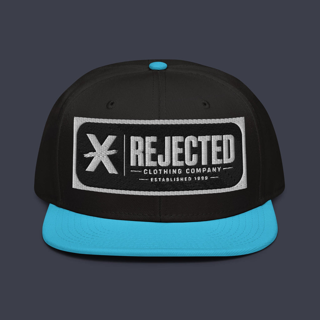Black snapback with a teal brim and an embroidered Rejected Clothing Company Established 1999 patch