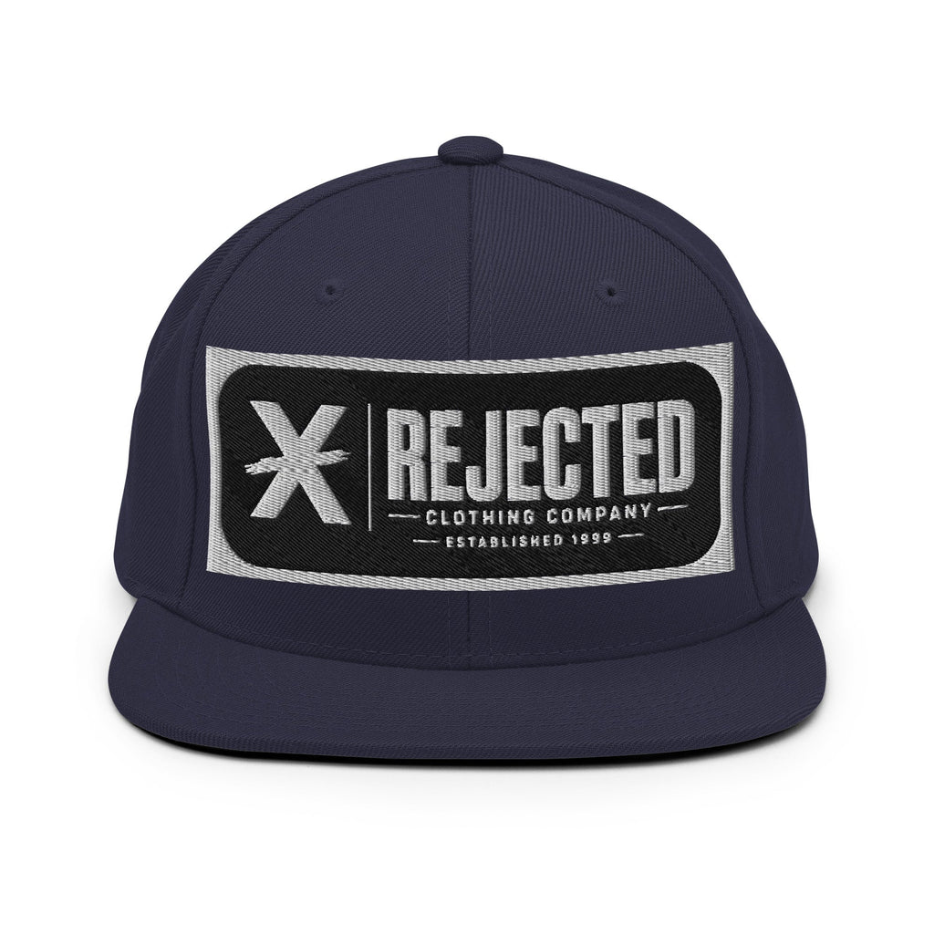 All-black snapback with an embroidered Rejected Clothing Company Established 1999 patch and a green undervisor