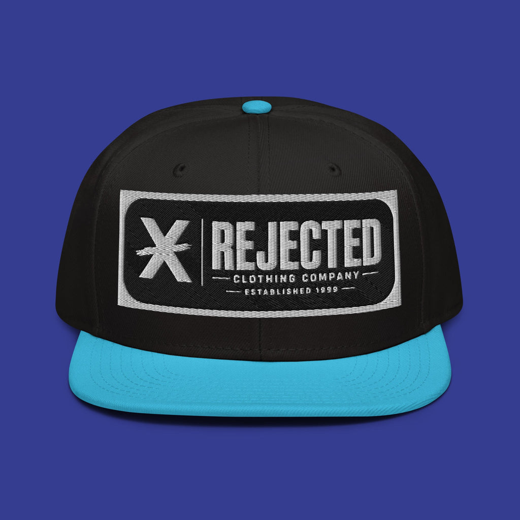 Black snapback with a teal brim and an embroidered Rejected Clothing Company Established 1999 patch