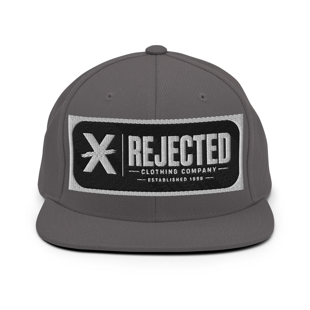All-black snapback with an embroidered Rejected Clothing Company Established 1999 patch and a green undervisor