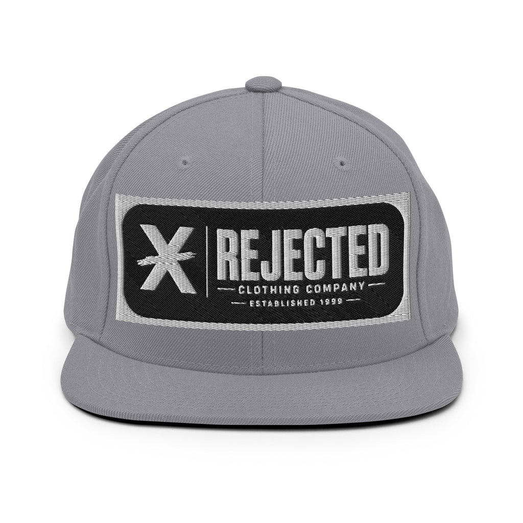All-black snapback with an embroidered Rejected Clothing Company Established 1999 patch and a green undervisor