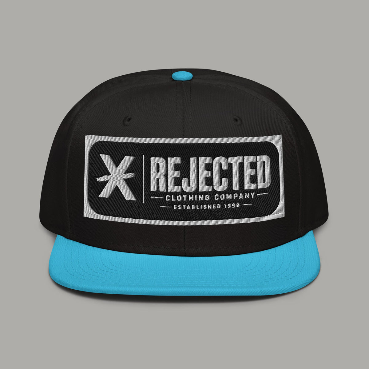 Black snapback with a teal brim and an embroidered Rejected Clothing Company Established 1999 patch