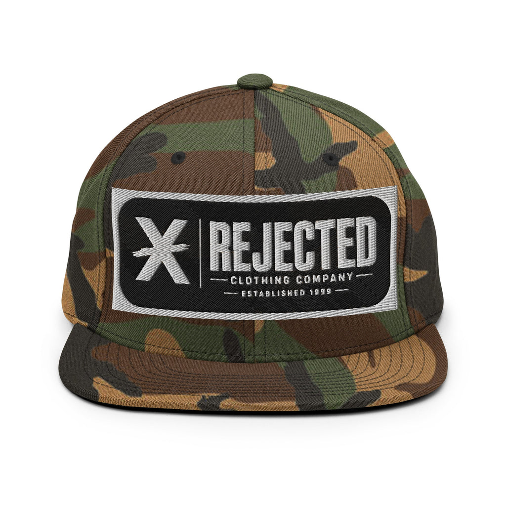 All-black snapback with an embroidered Rejected Clothing Company Established 1999 patch and a green undervisor