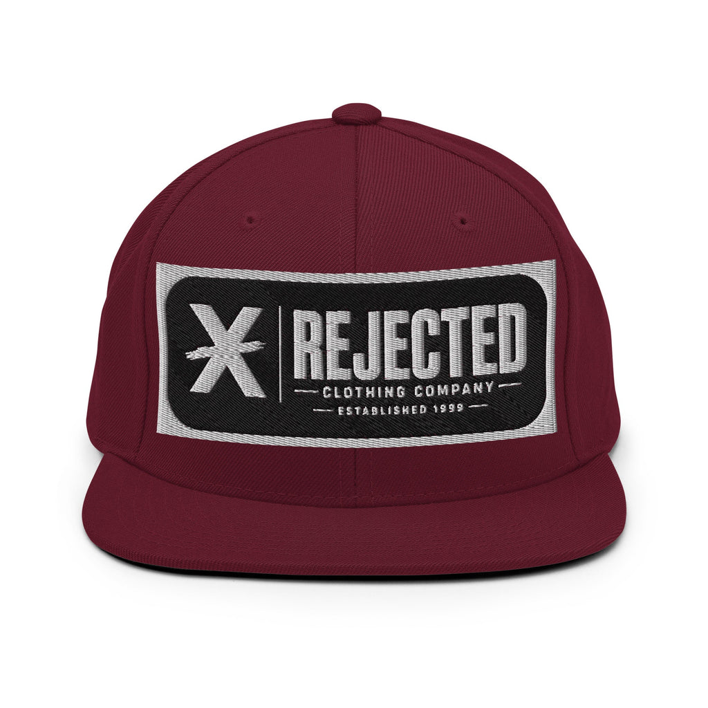 All-black snapback with an embroidered Rejected Clothing Company Established 1999 patch and a green undervisor