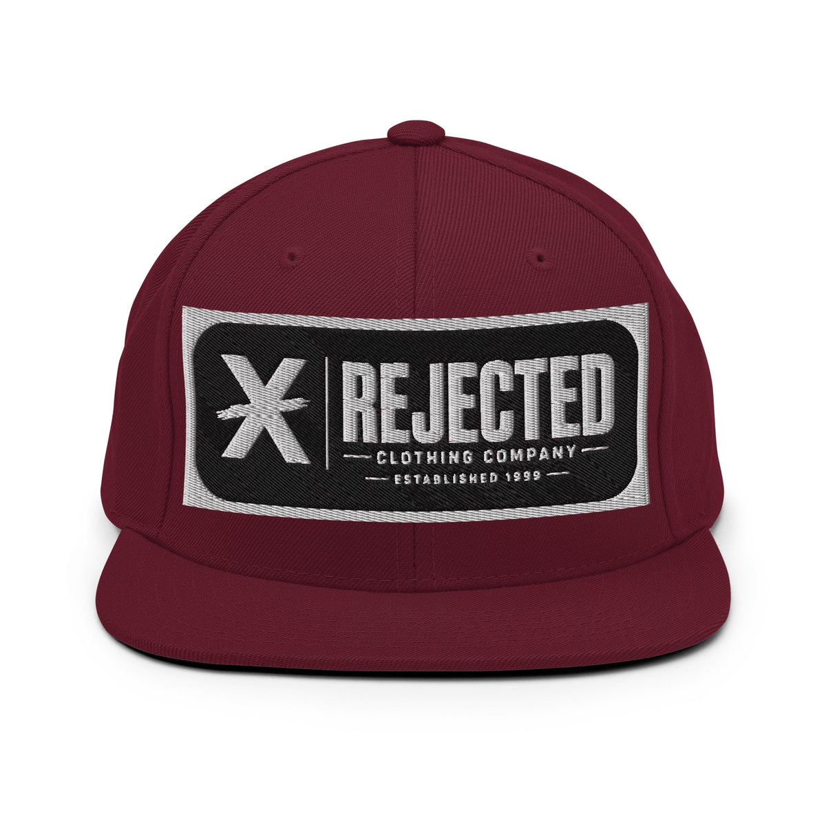 All-black snapback with an embroidered Rejected Clothing Company Established 1999 patch and a green undervisor