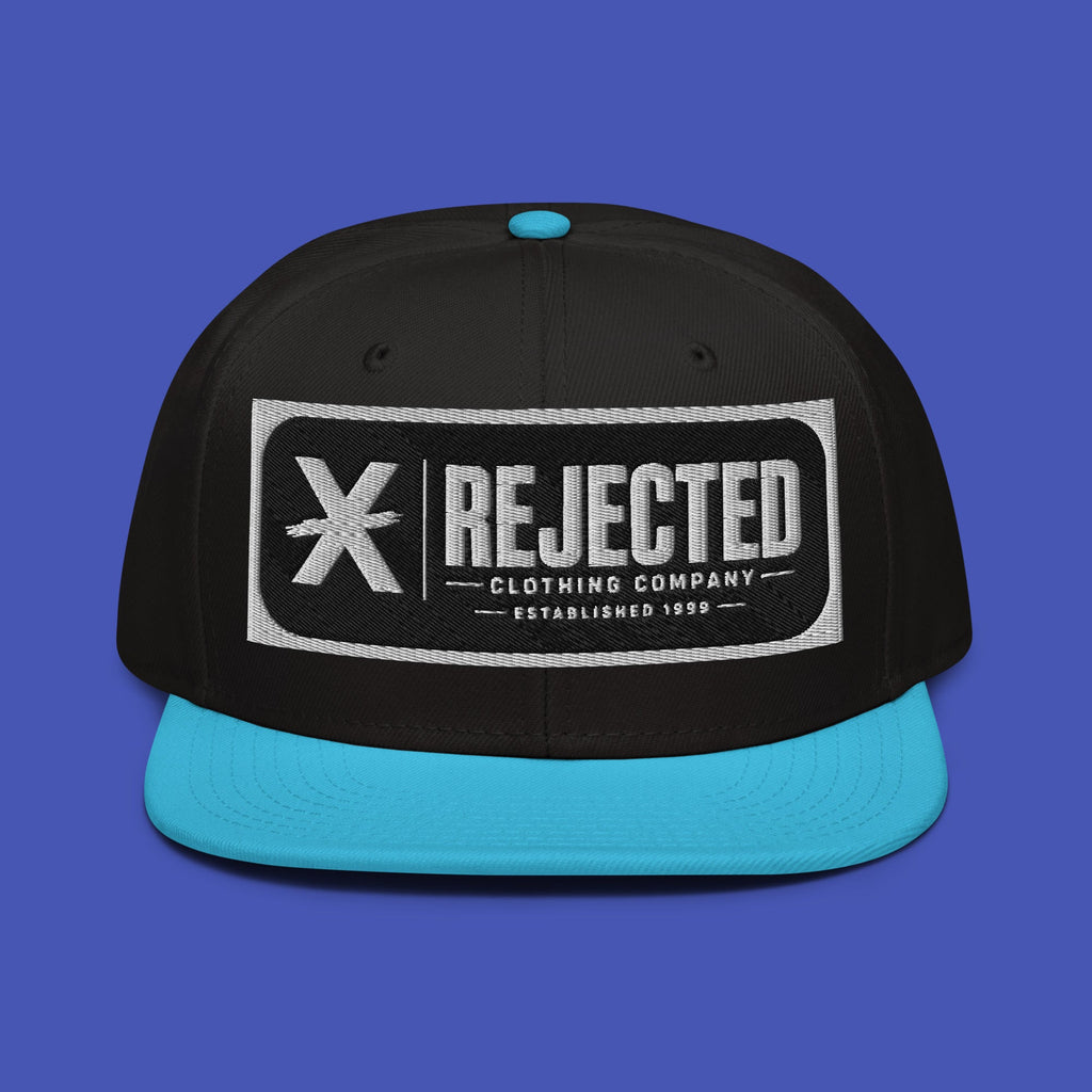 Black snapback with a teal brim and an embroidered Rejected Clothing Company Established 1999 patch