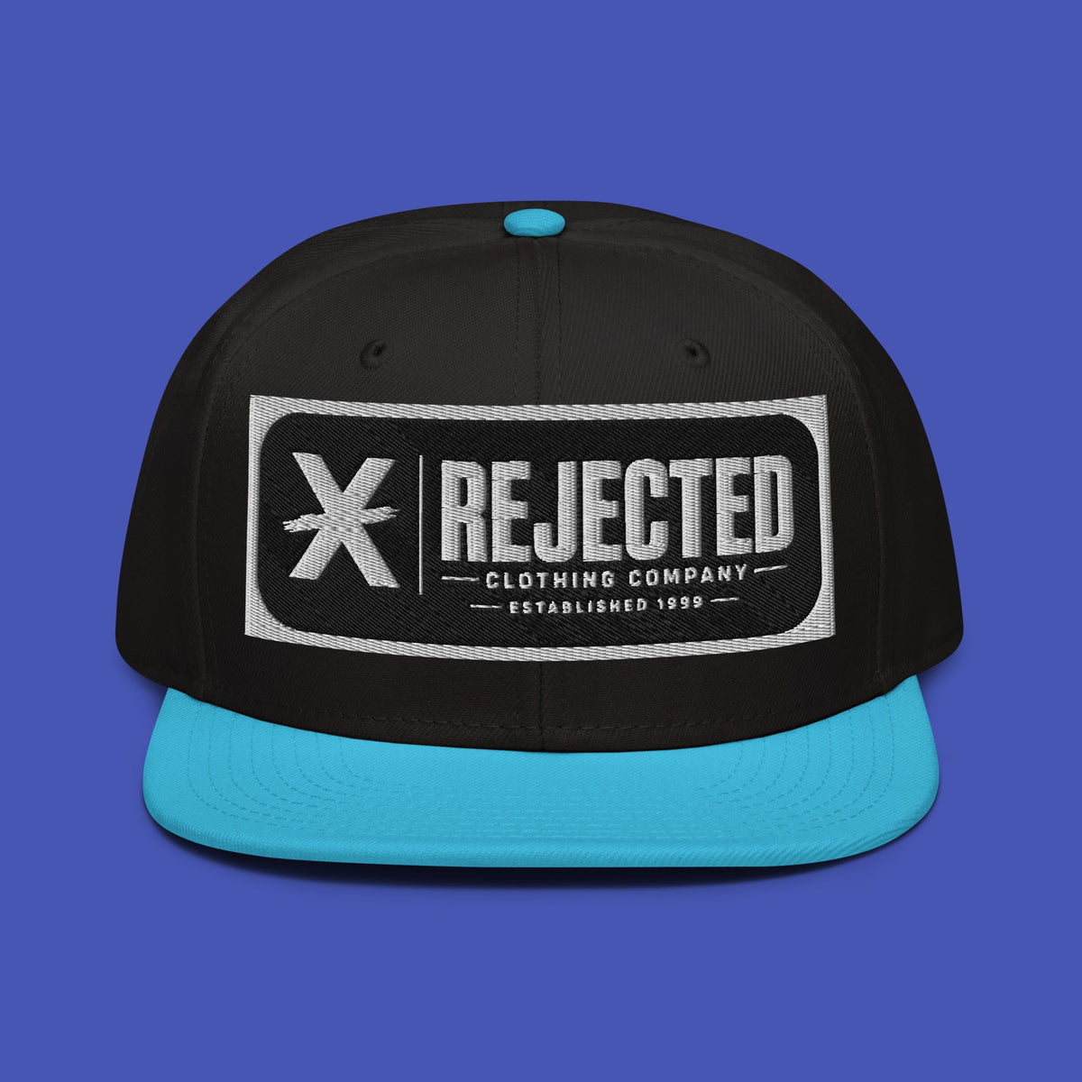 Black snapback with a teal brim and an embroidered Rejected Clothing Company Established 1999 patch