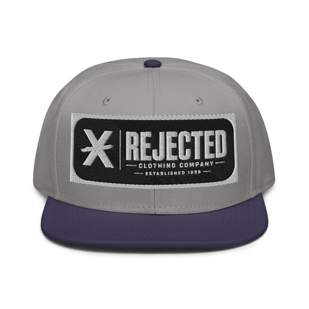 Black snapback with a teal brim and an embroidered Rejected Clothing Company Established 1999 patch